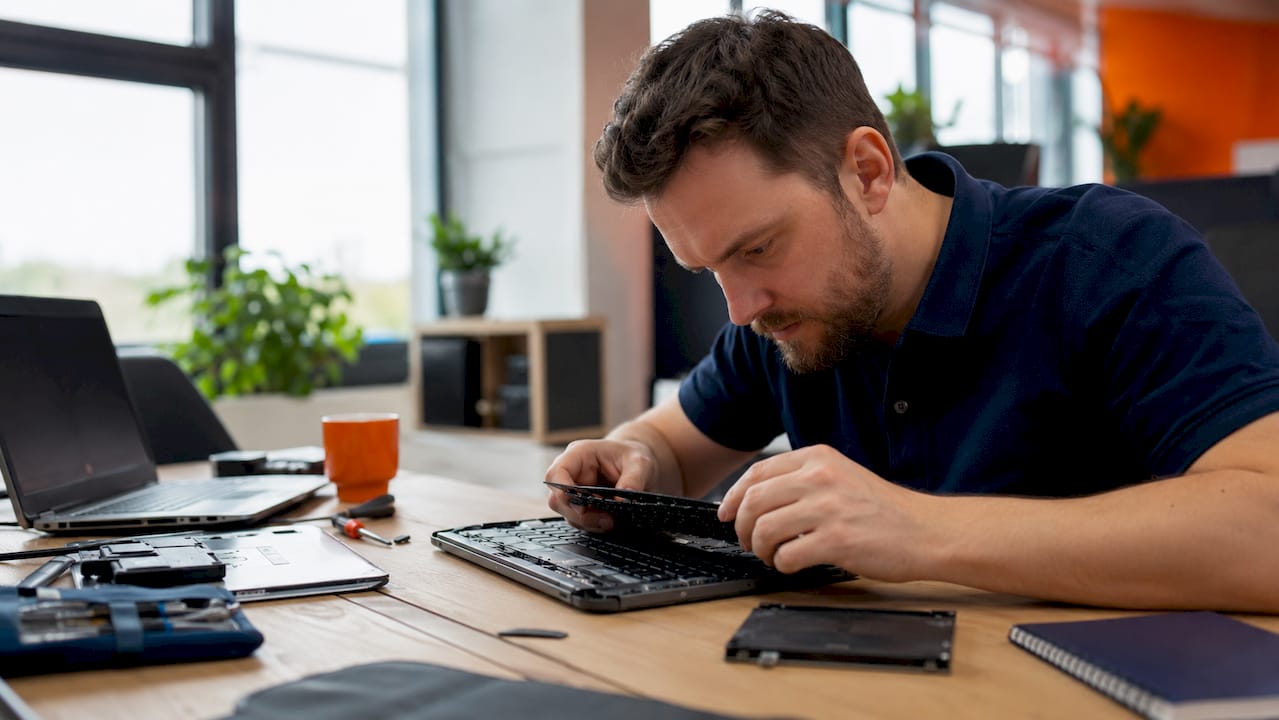 IT specialist troubleshooting laptop in office