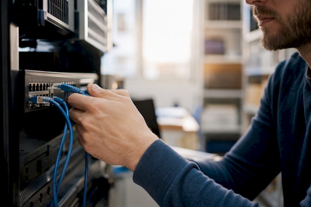 Technician hands unplugging network patch cable