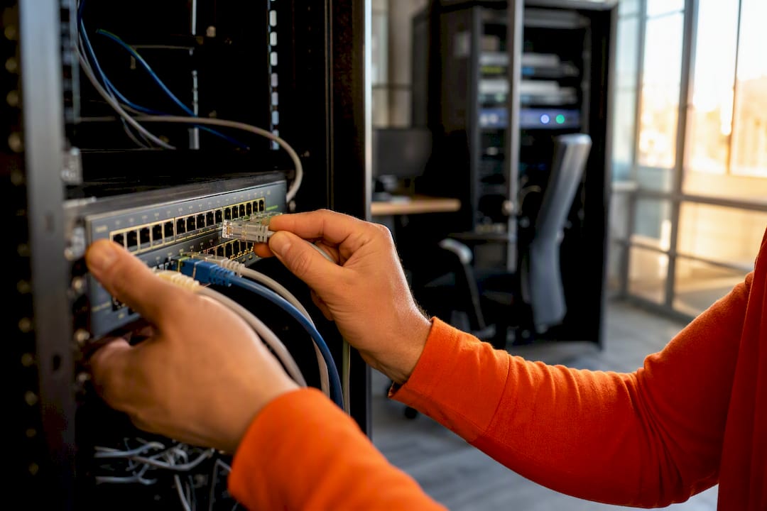 Hands connecting network cable in server room